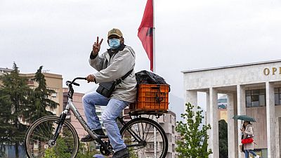 Un ciclista muestra el signo de la victoria en la plaza Skenderbeu de Tirana, la capital de Albania el viernes
