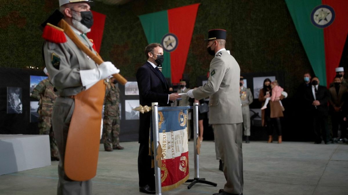Cumhurbaşkanı Emmanuel Macron bir lejyonere vatandaşlık belgesini verirken