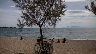 People sit a beach in Alimos, a seaside suburb of Athens, on Friday April 23, 2021.