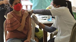 A woman reacts as she receives the AstraZeneca vaccine for COVID-19 at an apartment building in Bengaluru, India, Saturday, April 24, 2021.