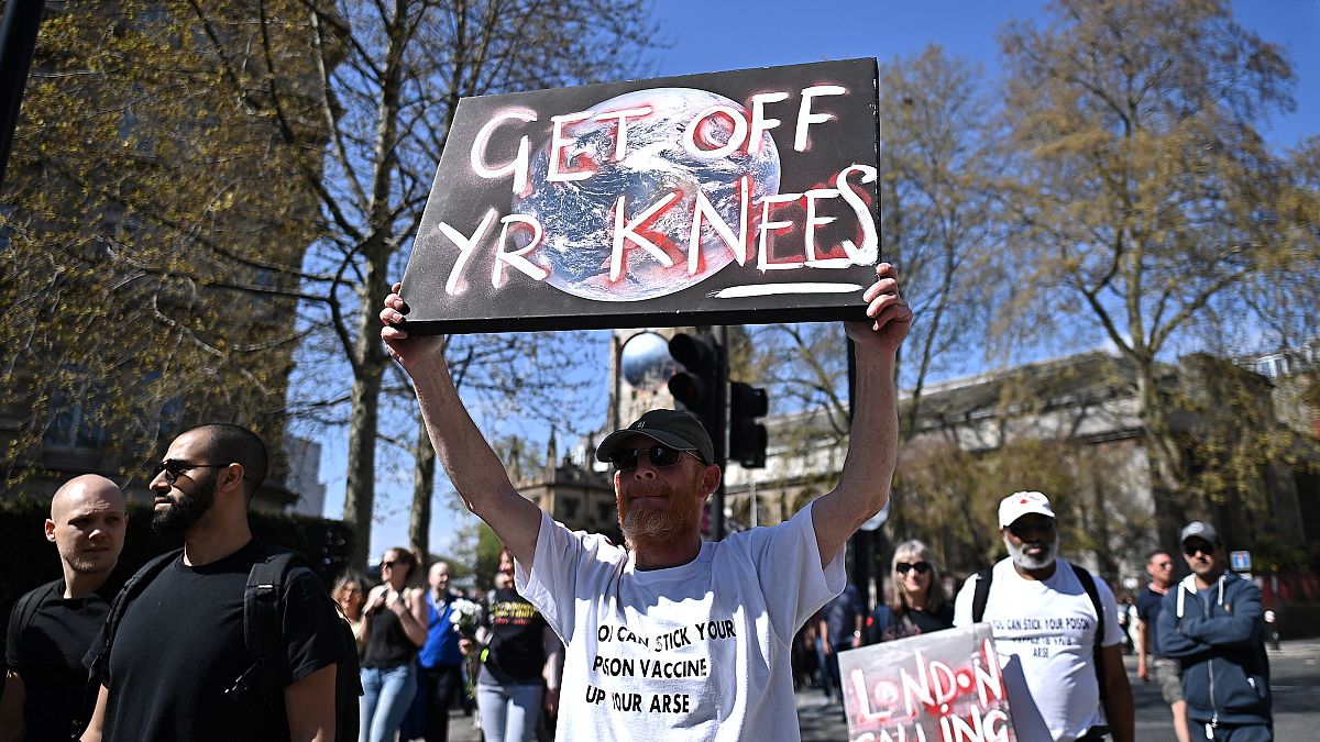 A man holds a placard aloft during anti-lockdown demonstrations in central London on Saturday