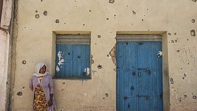A woman leans on the wall of a damaged house which was shelled as federal-aligned forces entered the city, in Wukro, north of Mekele, March 1, 2021