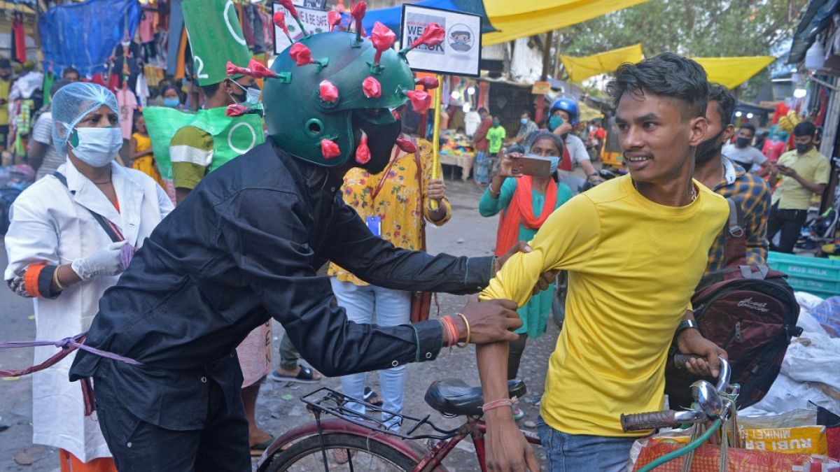 A man from a Non-governmental organization (NGO) wearing an outfit resembling the Covid-19 coronavirus moves around a marketplace urging people to follow the safety protocols 