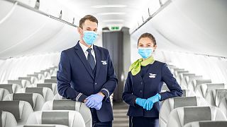 Members of the cabin crew welcome passengers on board an airBaltic flight during COVID-19.