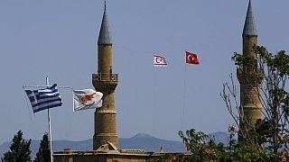 Greek, left, and Cyprus' flags, second left, flutter on poles in the south, as in the north Turkish occupied area, a Turkish & Turkish Cypriot breakaway flags fly on a minaret