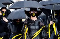 Women wearing black clothing and face masks with radioactivity sign march under umbrellas in Minsk. April 26, 2021