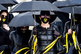 Women wearing black clothing and face masks with radioactivity sign march under umbrellas in Minsk. April 26, 2021