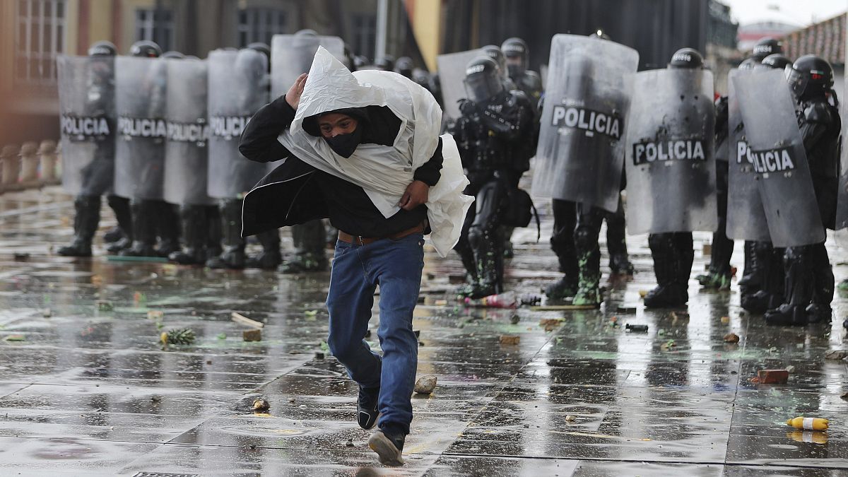 Un hombre huye de la policía tras lanzarle piedras durante una protesta en Colombia