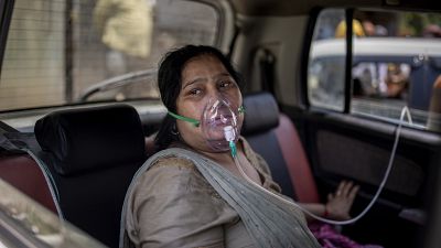 A COVID-19 patient sits inside a car and breathes with the help of oxygen