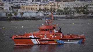 A wooden boat is towed by a Spanish Maritime Rescue Service ship.
