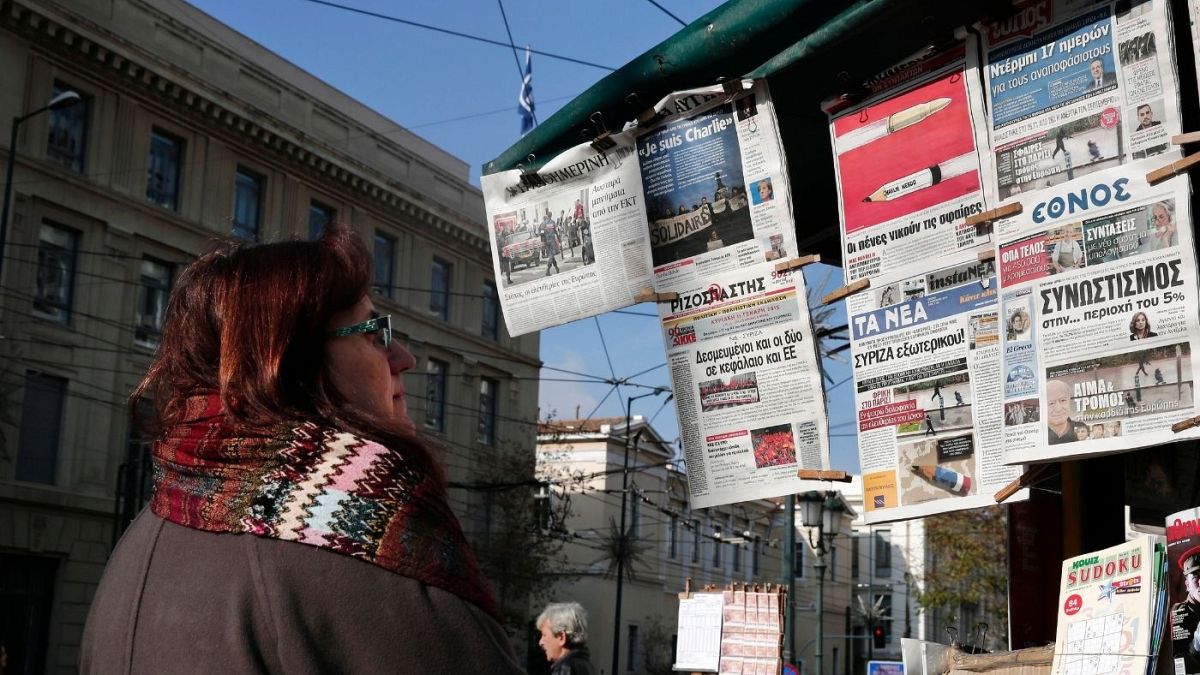 زنی در برابر یک کیوسک روزنامه‌فروشی در آتن پایتخت یونان 
