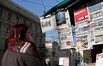 زنی در برابر یک کیوسک روزنامه‌فروشی در آتن پایتخت یونان