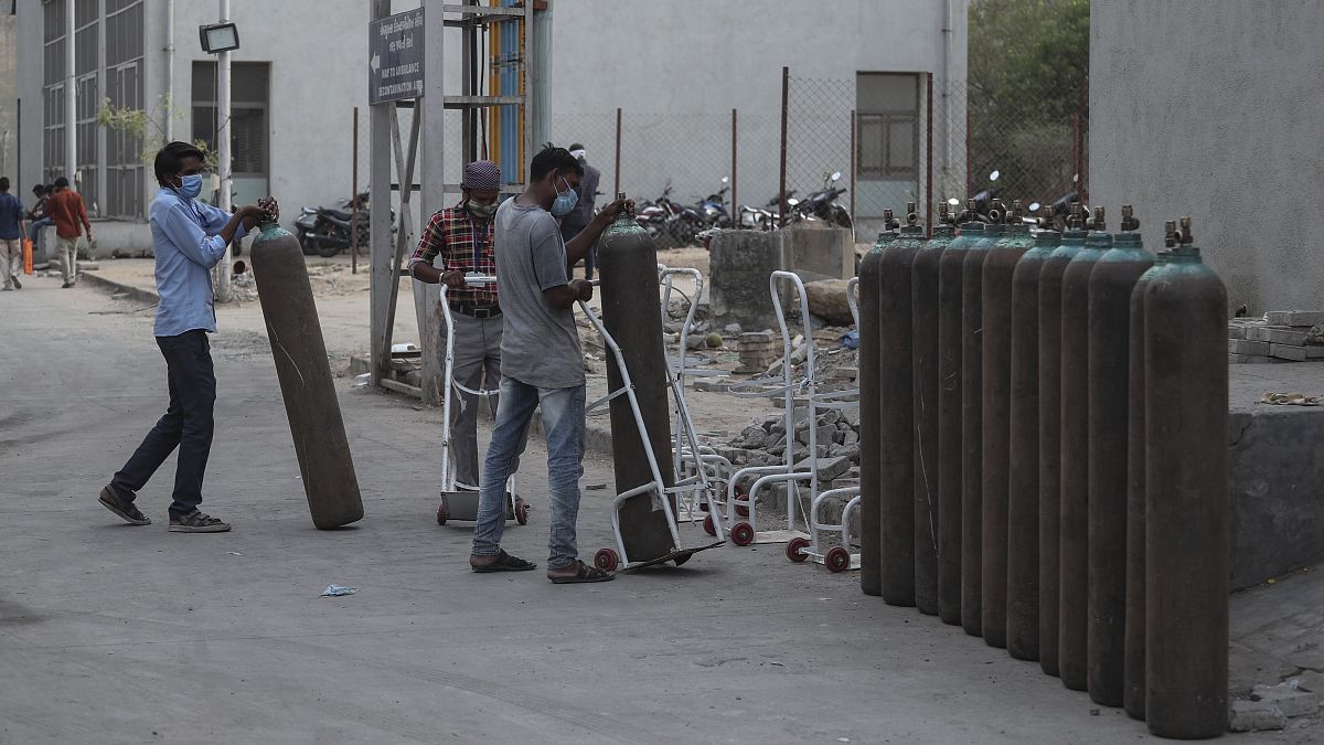Workers stack empty oxygen cylinders near an oxygen plant at a government COVID-19 hospital in Ahmedabad.