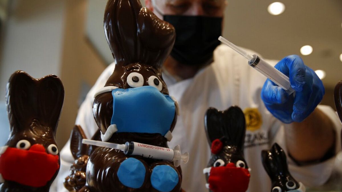 Tassos Vazakas, owner of a cake shop, prepares chocolate bunnies with masks and a vaccination syringe during Holy Week in Athens,