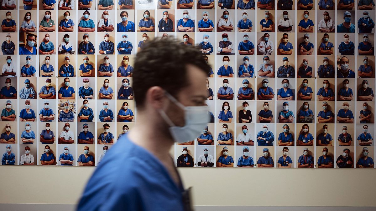 A member of staff passes in front of a collection of portraits of medical staff at Bichat Hospital, AP-HP, in Paris, Thursday, April 22, 2021.