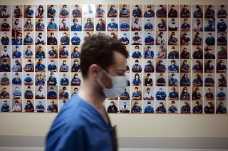 A member of staff passes in front of a collection of portraits of medical staff at Bichat Hospital, AP-HP, in Paris, Thursday, April 22, 2021.