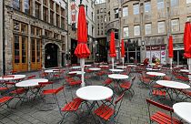 Empty tables are seen on a deserted square in the normally very busy old town of Cologne, Germany, Thursday, March 18, 2021.