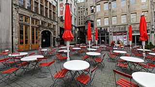 Empty tables are seen on a deserted square in the normally very busy old town of Cologne, Germany, Thursday, March 18, 2021.