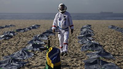 Tercio Galdino walks amid mock body bags representing COVID-19 victims on Copacabana beach.