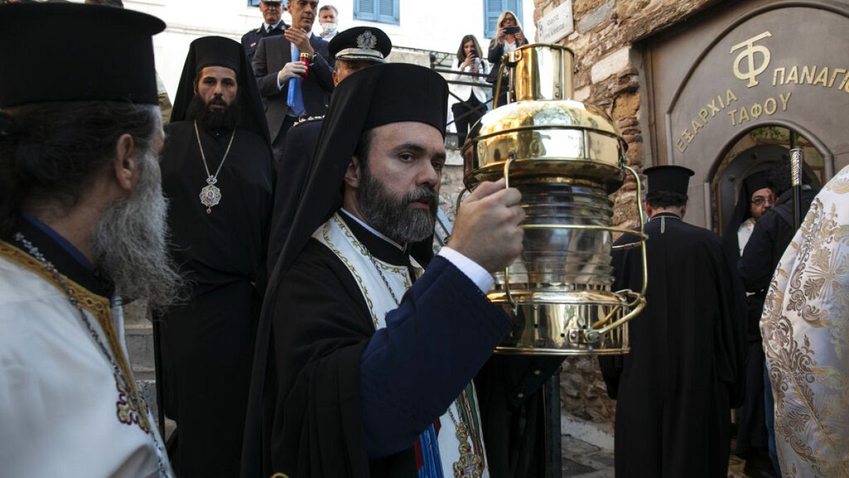 Greek Orthodox Archimandrite Damianos, center, arrives at the church of Agioi Anargyroi holding a cauldron with Holy Fire