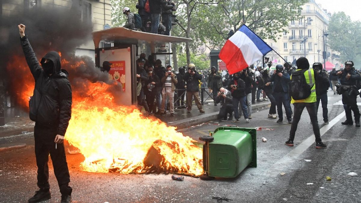 Protesters stand near a burning trash bin in the street during the annual May Day (Labour Day) rally in Paris on May 1, 2021.
