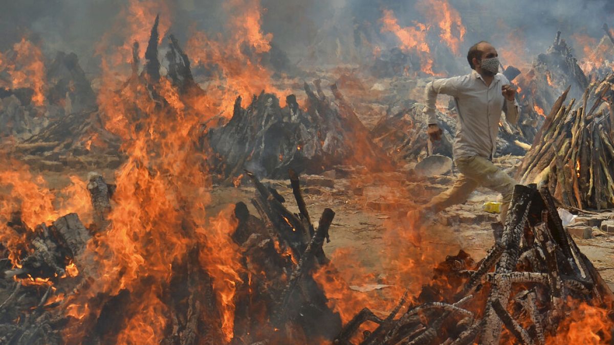 A man runs to escape heat emitting from the multiple funeral pyres of COVID-19 victims at a crematorium in the outskirts of New Delhi, India, Thursday, April 29, 2021.