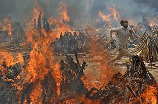 A man runs to escape heat emitting from the multiple funeral pyres of COVID-19 victims at a crematorium in the outskirts of New Delhi, India, Thursday, April 29, 2021.