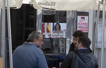 People sit outside a bar with a poster of the president of the Madrid autonomous government, Isabel Diaz Ayuso, on March 22, 2021.