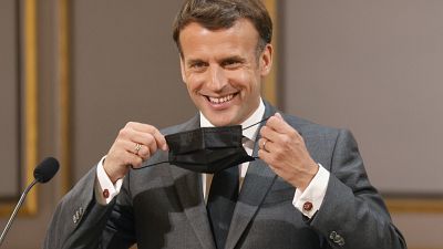 French President Emmanuel Macron removing his protective face mask before delivering a speech