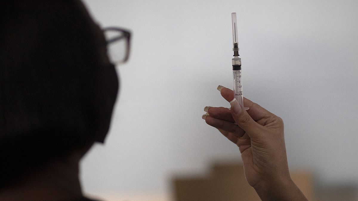 28 aprile 2021: a Rio de Janeiro, in Brasile, un'operatrice sanitaria mostra a una paziente una siringa con una dose del vaccino Sinovac  