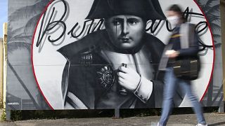 A woman walks past a picture of Napoleon Bonaparte in Corsica ahead of the bicentennial of his death.