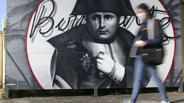A woman walks past a picture of Napoleon Bonaparte in Corsica ahead of the bicentennial of his death.