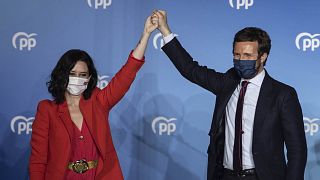 Conservative Madrid regional president Isabel Diaz Ayuso, left, and Popular party leader Pablo Casasdo wave outside the popular party headquarters in Madrid, Spain.