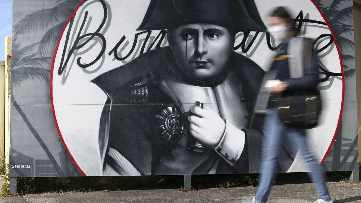 Eine Frau geht an einem Bild von Napoleon Bonaparte in Korsika vorbei