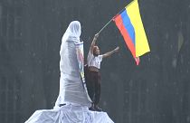Un chica ondea una bandera de colombia subida en una estatua en el inicio del paro nacional de este miércoles 5 de mayo de 2021