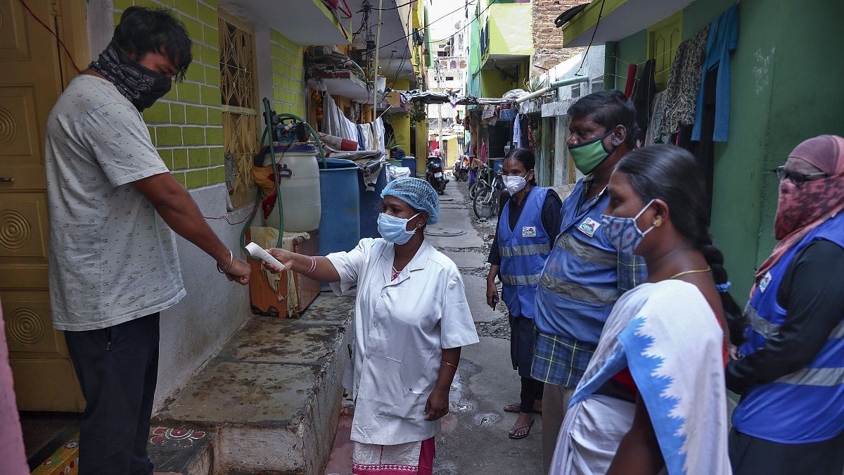 An Indian health worker checks body temperature of a man during a door-to-door survey being conducted as a precaution against COVID-19 in Hyderabad, India, May 6, 2021