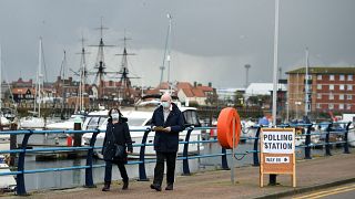 A couple walks past a sign for a Polling Station beside the marina in Hartlepool, north-east England on May 6, 2021
