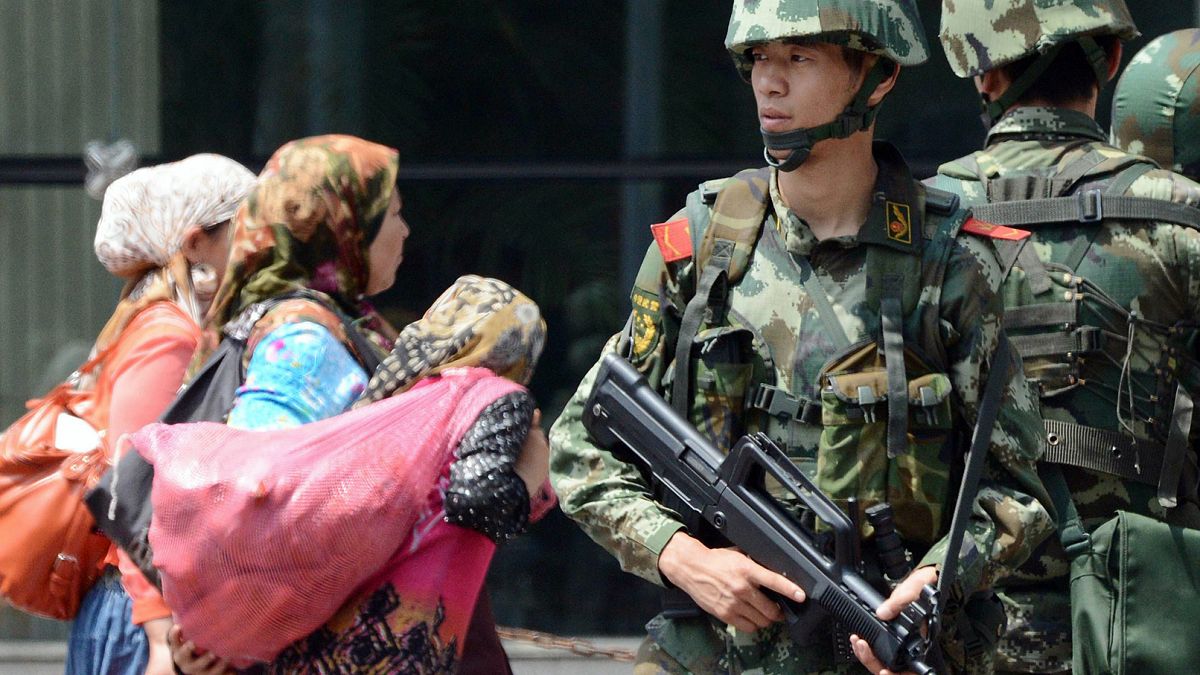 Doğu Türkistan'ın başkenti Urumçi'de Çinli paramiliter güçler ve buradan geçen Uygur kadınlar (arşiv)
