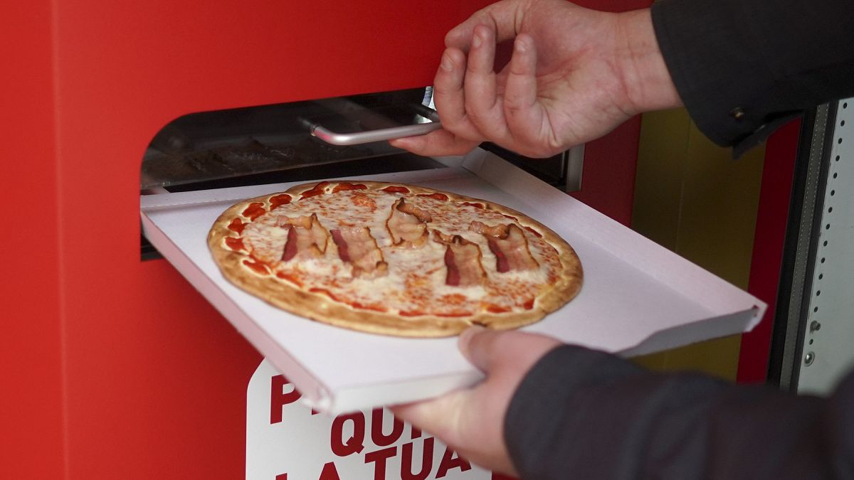Elkészült pizzát vesz ki egy férfi az automatából