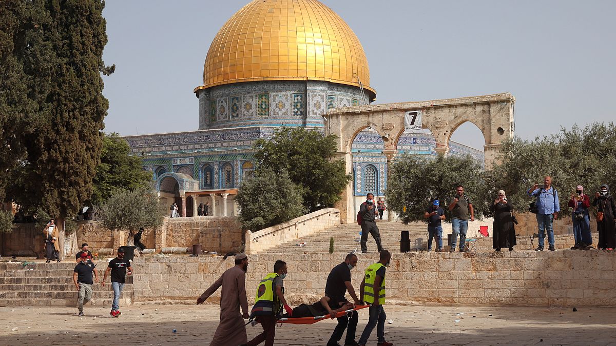 Palestinians evacuate a wounded man during clashes with Israeli security forces in front of the Dome of the Rock Mosque