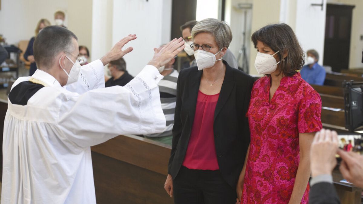 Vicar Wolfgang Rothe blesses Christine Walter and Almut Muenster at St Benedict's Church, Munich