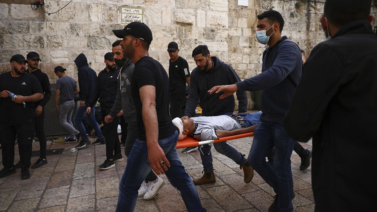 فلسطينيون بحملون متظاهرا مصابا خلال مواجهات مع قوات الأمن الإسرائيلية قرب باب الأسباط، البلدة القديمة بالقدس، الإثنين، 10 مايو، 2021