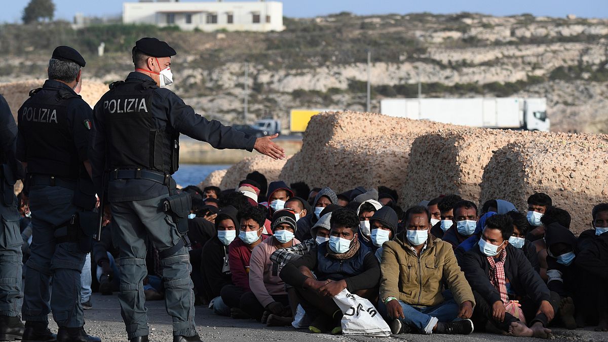 Les migrants arrivés sur l'île de Lampedusa en Italie attendent sur le quai, le 10 mai 2021