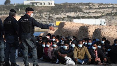 Les migrants arrivés sur l'île de Lampedusa en Italie attendent sur le quai, le 10 mai 2021