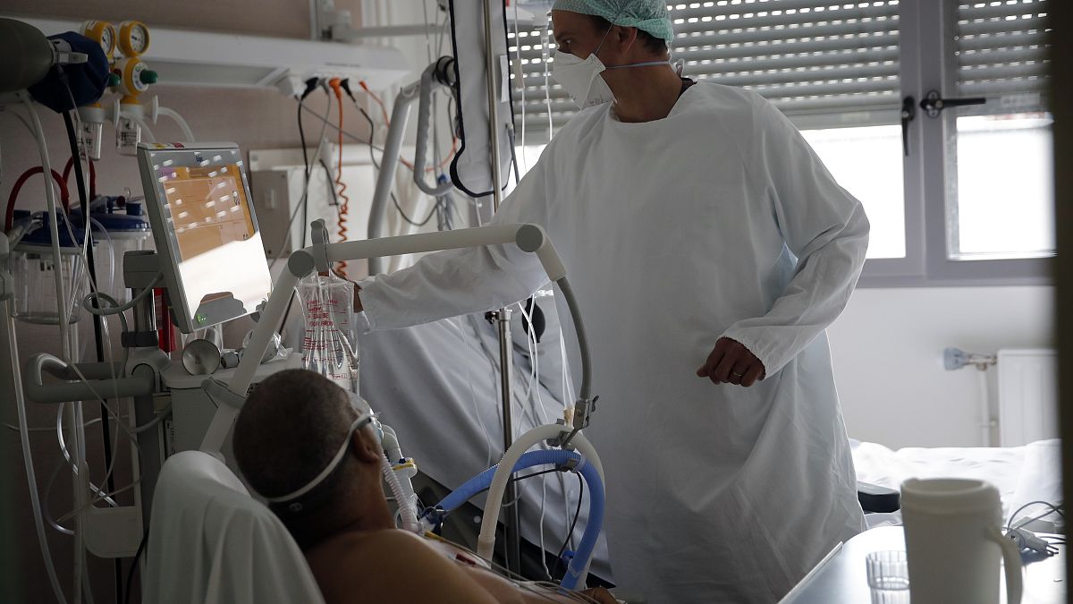 أحد أعضاء الطاقم الطبي يعتني بمريض مصاب بفيروس كورونا في وحدة العناية المركزة في مستشفى شارل نيكول العام في روان - فرنسا