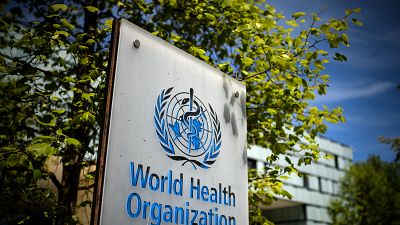 يافطة تحمل شعار منظمة الصحة العالمية أمام مكتبها في مدينة جنيف السويسرية