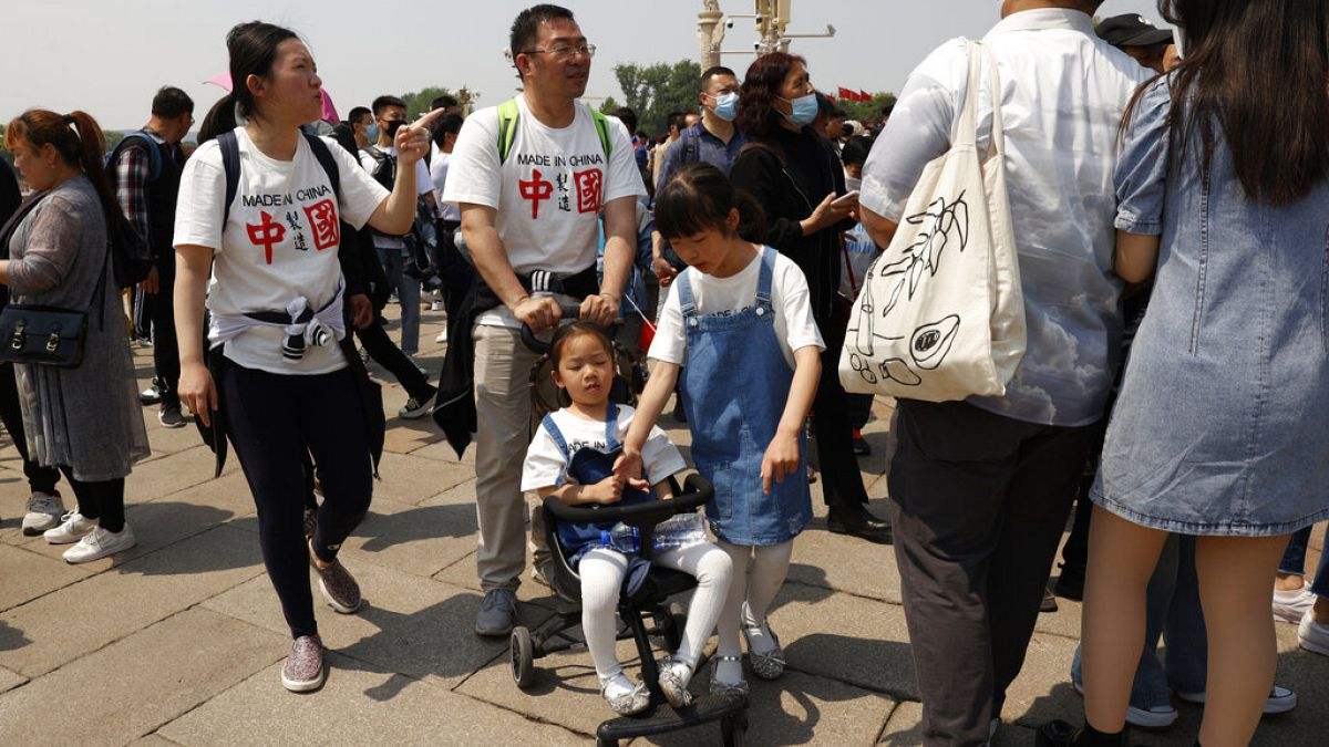Residents wearing t-shirts which reads "Made In China" visit Tiananmen Gate with two children in Beijing