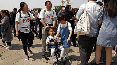 Residents wearing t-shirts which reads "Made In China" visit Tiananmen Gate with two children in Beijing