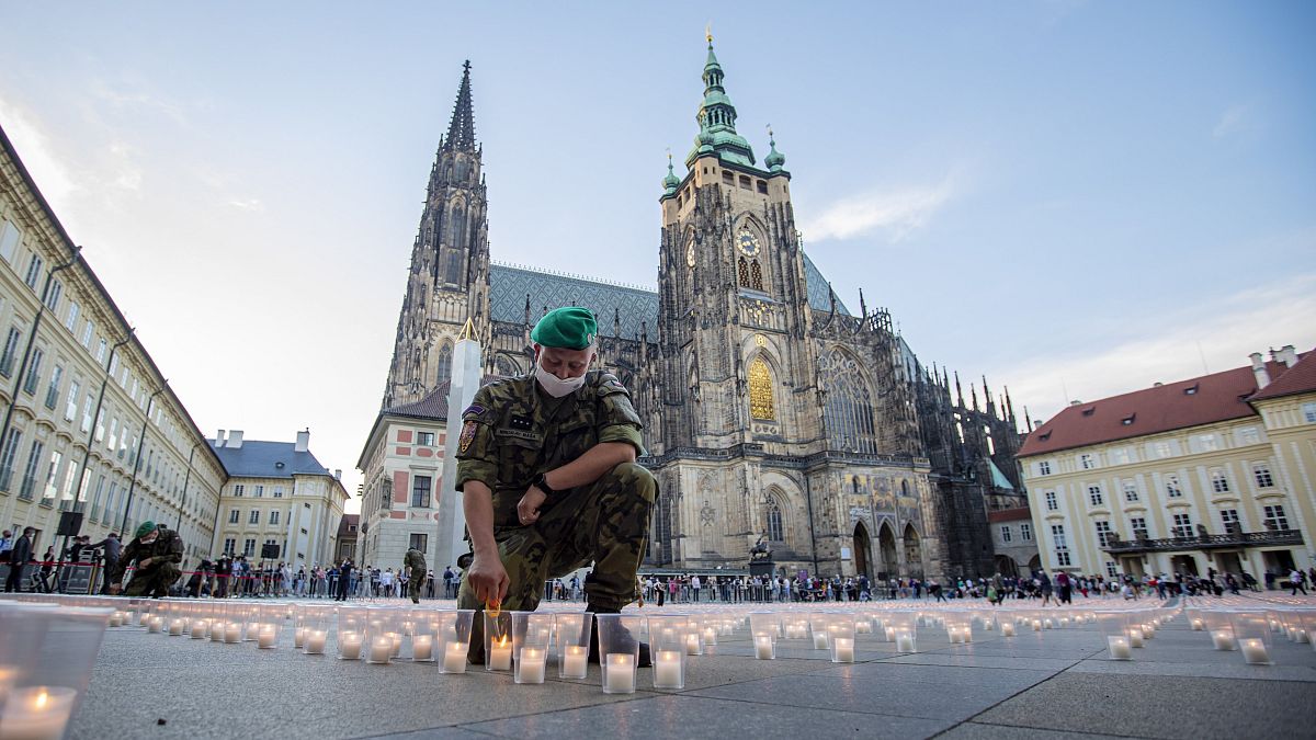Egy katona meggyújtja a koronavírus csehországi áldozatainak emlékére elhelyezett közel 30 ezer mécses egyikét a prágai várnál 2021. május 10-én