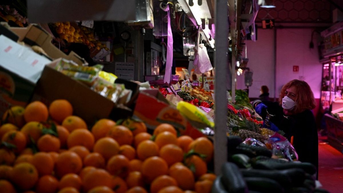 A woman checks fruit and vegetables at the Cebada market in Madrid